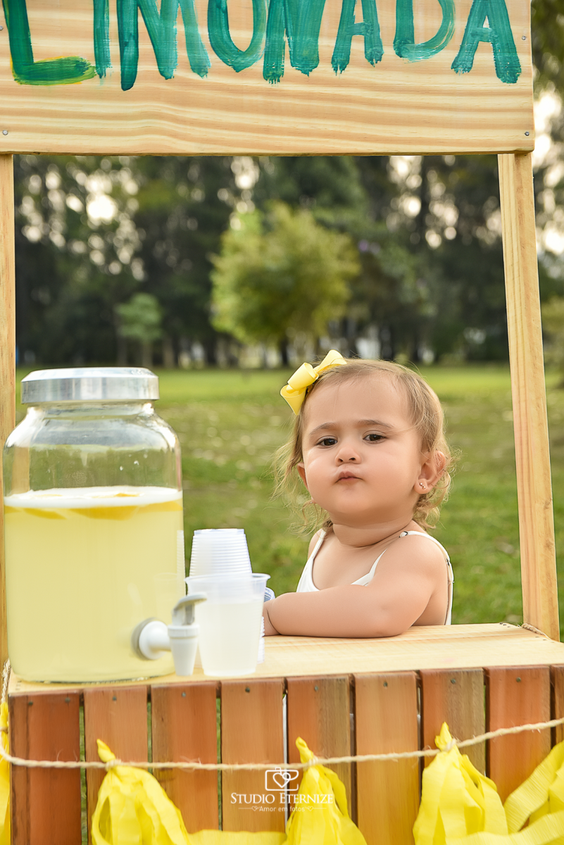 Sessão fotográfica infantil externa com cenário da barraca da limonada. Close da criança que estava atrás da barraca da limonada fazendo biquinho.