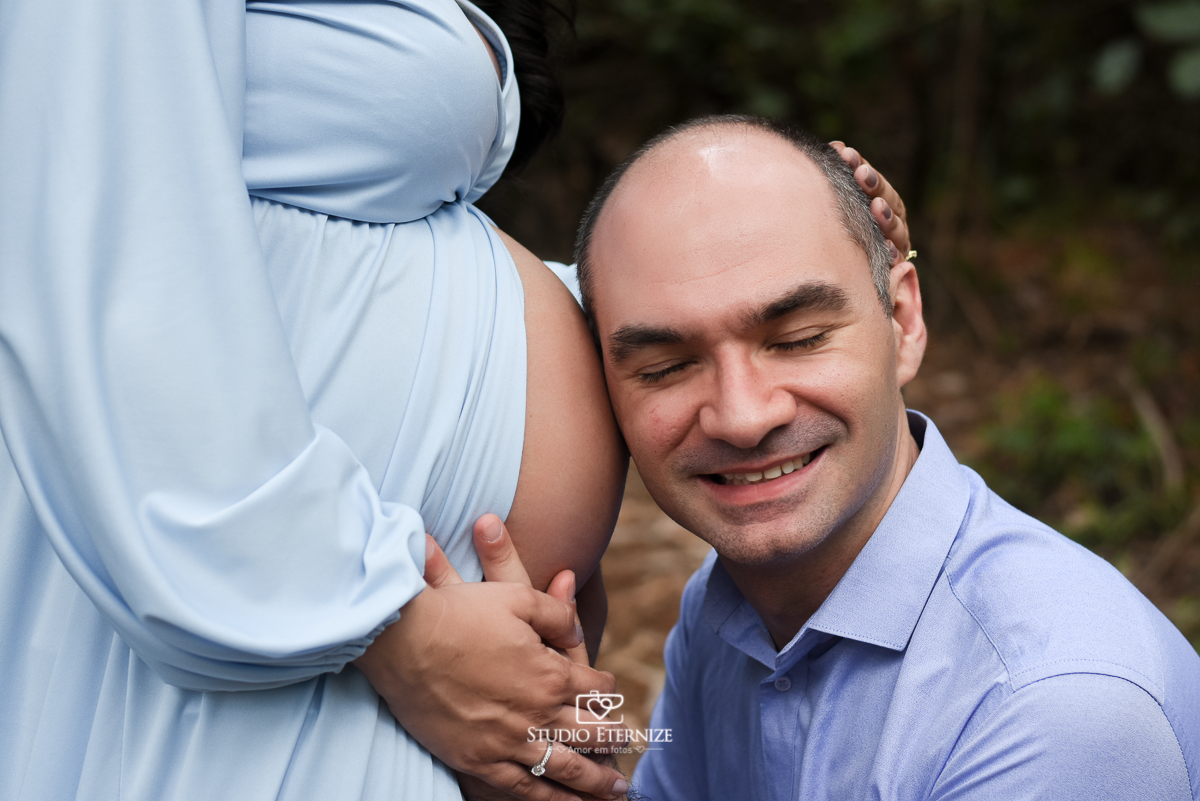 Ensaio fotográfico de gestante da Juliana na Rapa de Paraglider em Poços de caldas. Detalhe de perfil da barriga da gestante. Seu esposo de olhos fechados. encostado seu ouvido na sua barriga.