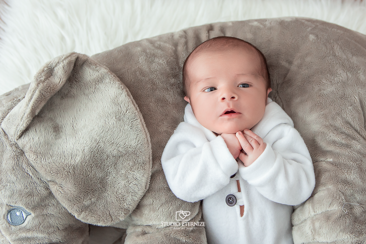 Fotografia newborn menino realizada pelo Studio Eternize em Poços de Caldas - MG. Bebê de roupinha e olhos abertos.