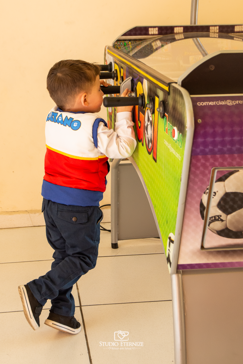 Fotografia de festa infantil de 3 anos registrada pelo Studio Eternize no tema da Patrulha Canina em no Buffet Cata-Vento em Poços de Caldas - MG. Aniversariante brincando na mesa de pebolim.