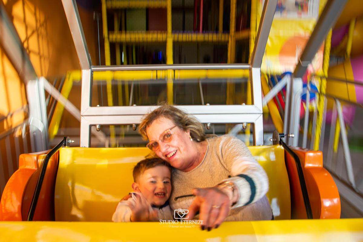 Fotografia de festa infantil de 3 anos registrada pelo Studio Eternize no tema da Patrulha Canina em no Buffet Cata-Vento em Poços de Caldas - MG. Aniversariante brincando com a avó no barco.