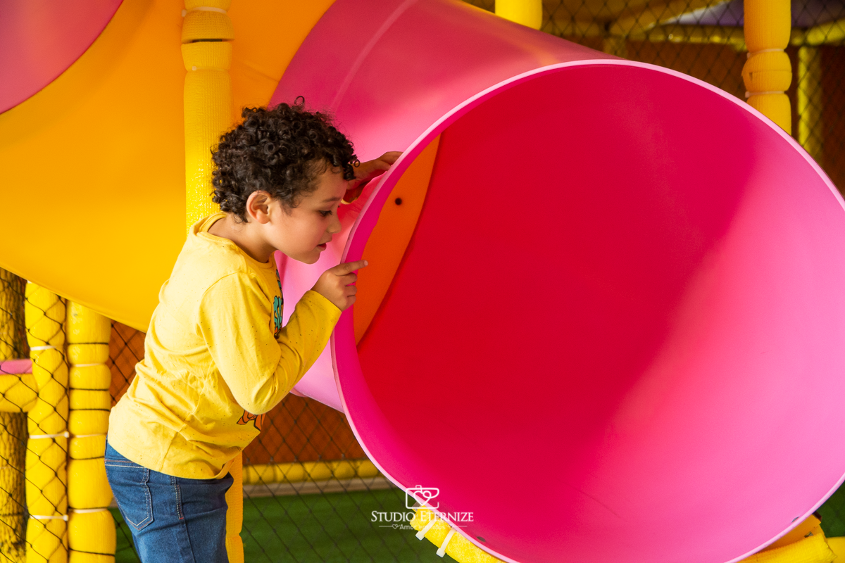 Fotografia de festa infantil de 3 anos registrada pelo Studio Eternize no tema da Patrulha Canina em no Buffet Cata-Vento em Poços de Caldas - MG. Aniversariante brincando no escorrega.