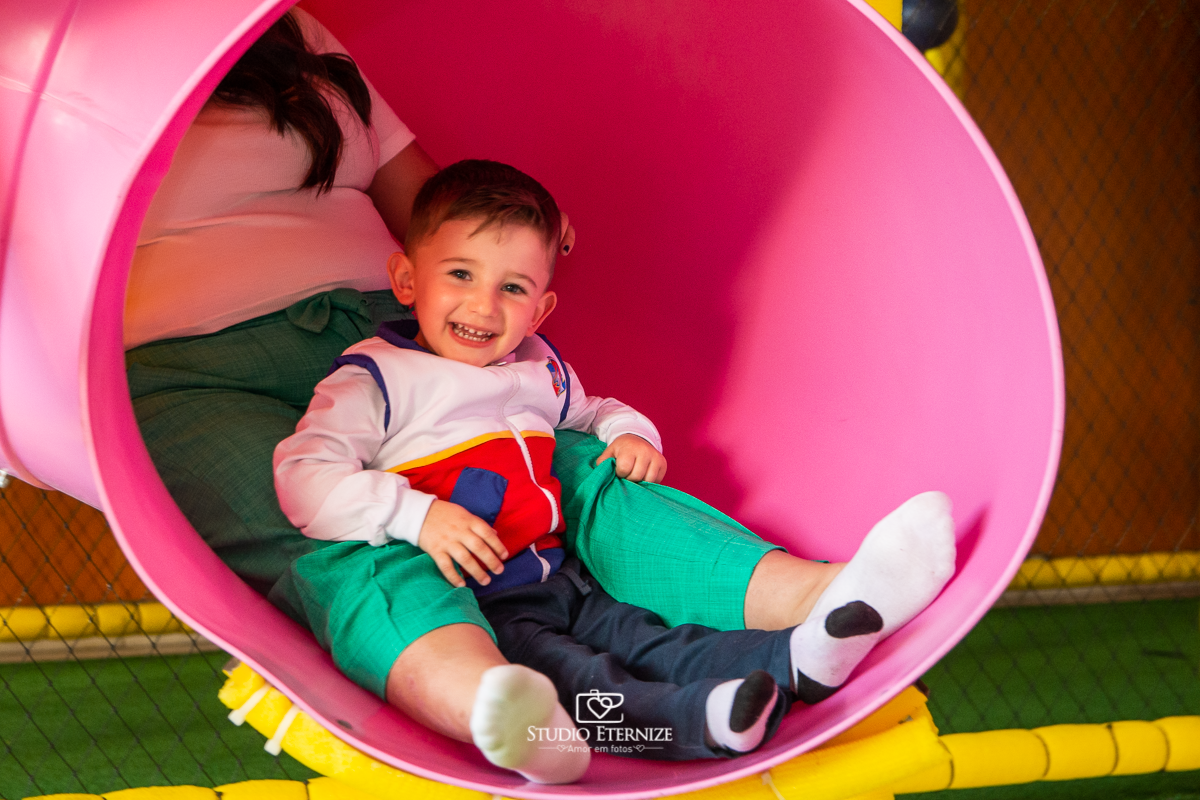 Fotografia de festa infantil de 3 anos registrada pelo Studio Eternize no tema da Patrulha Canina em no Buffet Cata-Vento em Poços de Caldas - MG. Aniversariante brincando no escorrega com sua mãe.