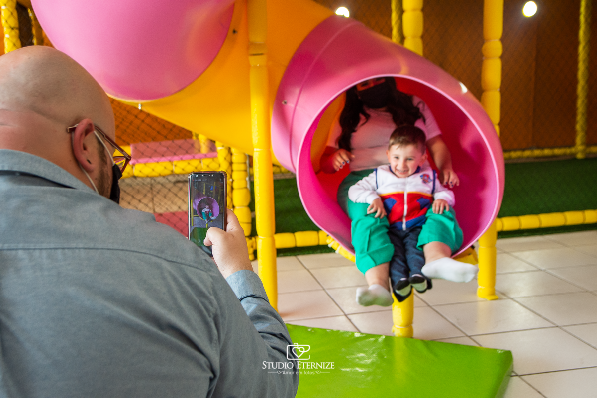 Fotografia de festa infantil de 3 anos registrada pelo Studio Eternize no tema da Patrulha Canina em no Buffet Cata-Vento em Poços de Caldas - MG. Aniversariante brincando no escorrega com sua mãe.