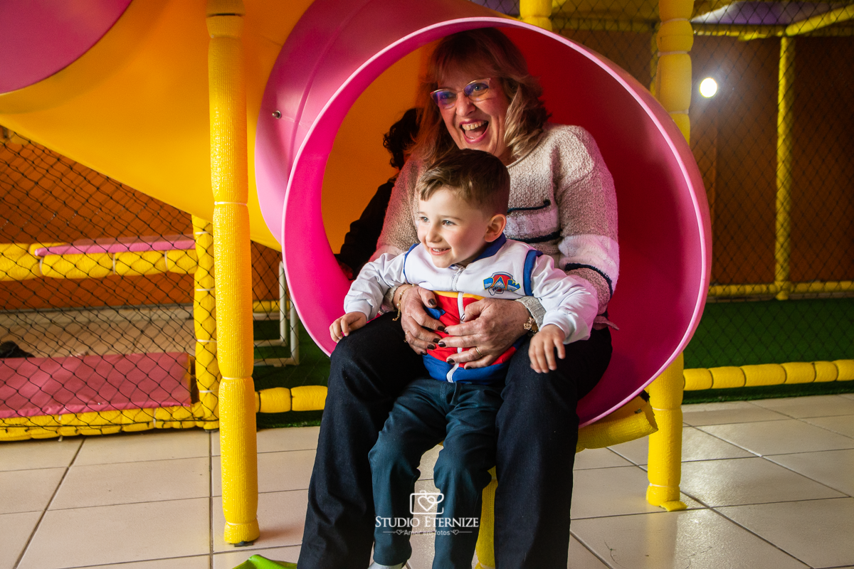 Fotografia de festa infantil de 3 anos registrada pelo Studio Eternize no tema da Patrulha Canina em no Buffet Cata-Vento em Poços de Caldas - MG. Aniversariante brincando no escorrega com sua avó.