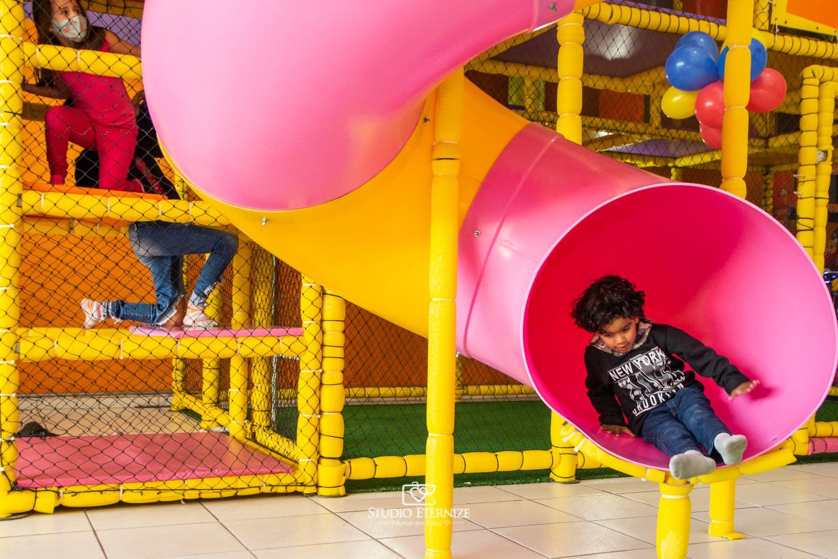 Fotografia de festa infantil de 3 anos registrada pelo Studio Eternize no tema da Patrulha Canina em no Buffet Cata-Vento em Poços de Caldas - MG. Criança brincando no escorrega.