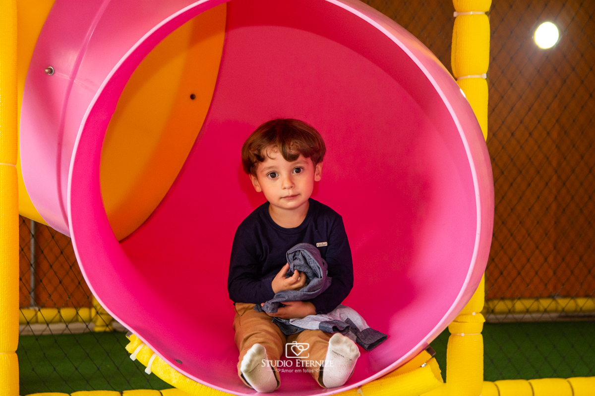 Fotografia de festa infantil de 3 anos registrada pelo Studio Eternize no tema da Patrulha Canina em no Buffet Cata-Vento em Poços de Caldas - MG. Criança brincando no escorrega.