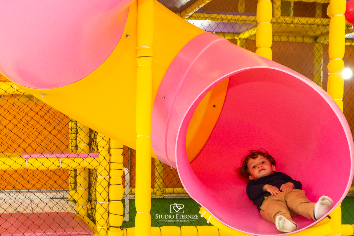 Fotografia de festa infantil de 3 anos registrada pelo Studio Eternize no tema da Patrulha Canina em no Buffet Cata-Vento em Poços de Caldas - MG. Aniversariante brincando no escorrega.