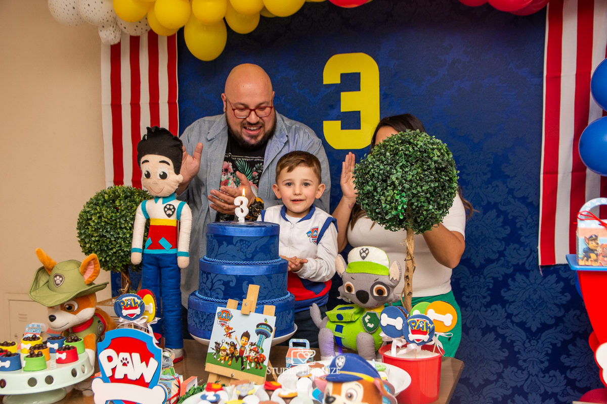 Fotografia de festa infantil de 3 anos registrada pelo Studio Eternize no tema da Patrulha Canina em no Buffet Cata-Vento em Poços de Caldas - MG. Aniversariante e seus pais cantando parabéns.