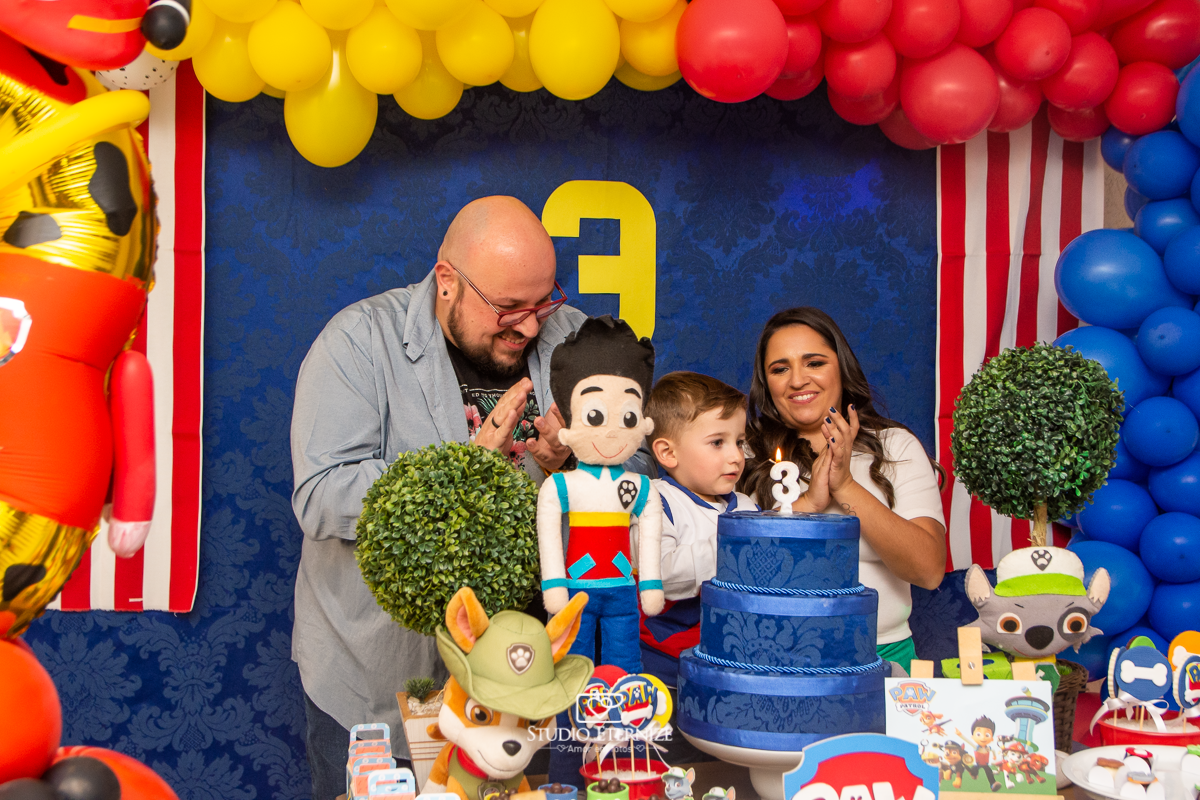 Fotografia de festa infantil de 3 anos registrada pelo Studio Eternize no tema da Patrulha Canina em no Buffet Cata-Vento em Poços de Caldas - MG. Aniversariante e seus pais cantando parabéns.
