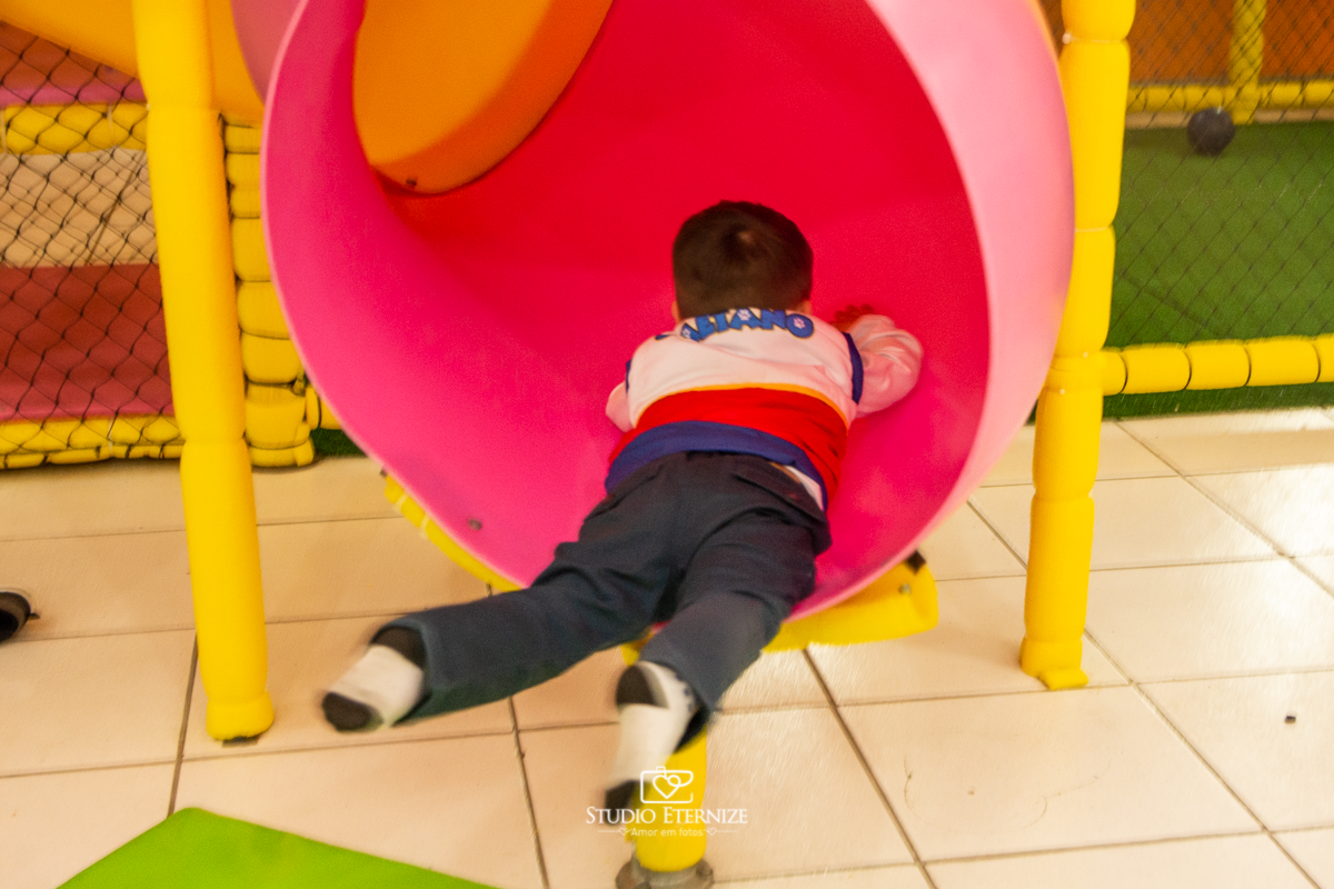Fotografia de festa infantil de 3 anos registrada pelo Studio Eternize no tema da Patrulha Canina em no Buffet Cata-Vento em Poços de Caldas - MG. Aniversariante brincando no escorrega.