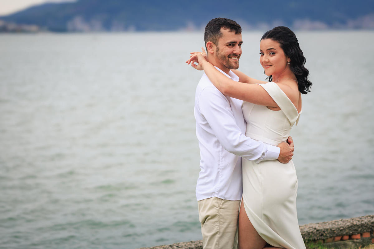 Djonata e Aline se abraçando, com o pôr do sol ao fundo, trazendo uma atmosfera de carinho e cumplicidade.