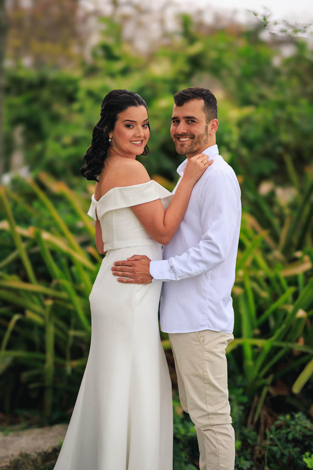 Djonata e Aline em um abraço carinhoso, transmitindo cumplicidade e conexão, com a paisagem de Coqueiros ao fundo.