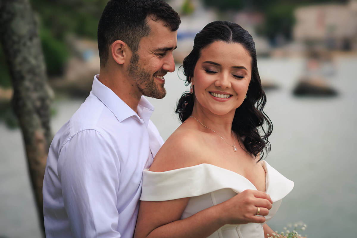 Djonata e Aline em um abraço carinhoso, transmitindo cumplicidade e conexão, com a paisagem de Coqueiros ao fundo.