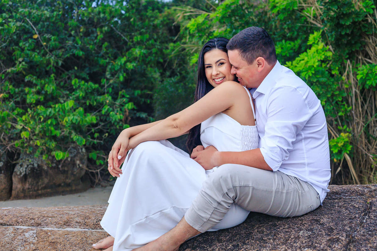 Casal abraçado em ensaio na Praia de Canajure. Ensaio de Amor em Florianópolis com vestido branco.