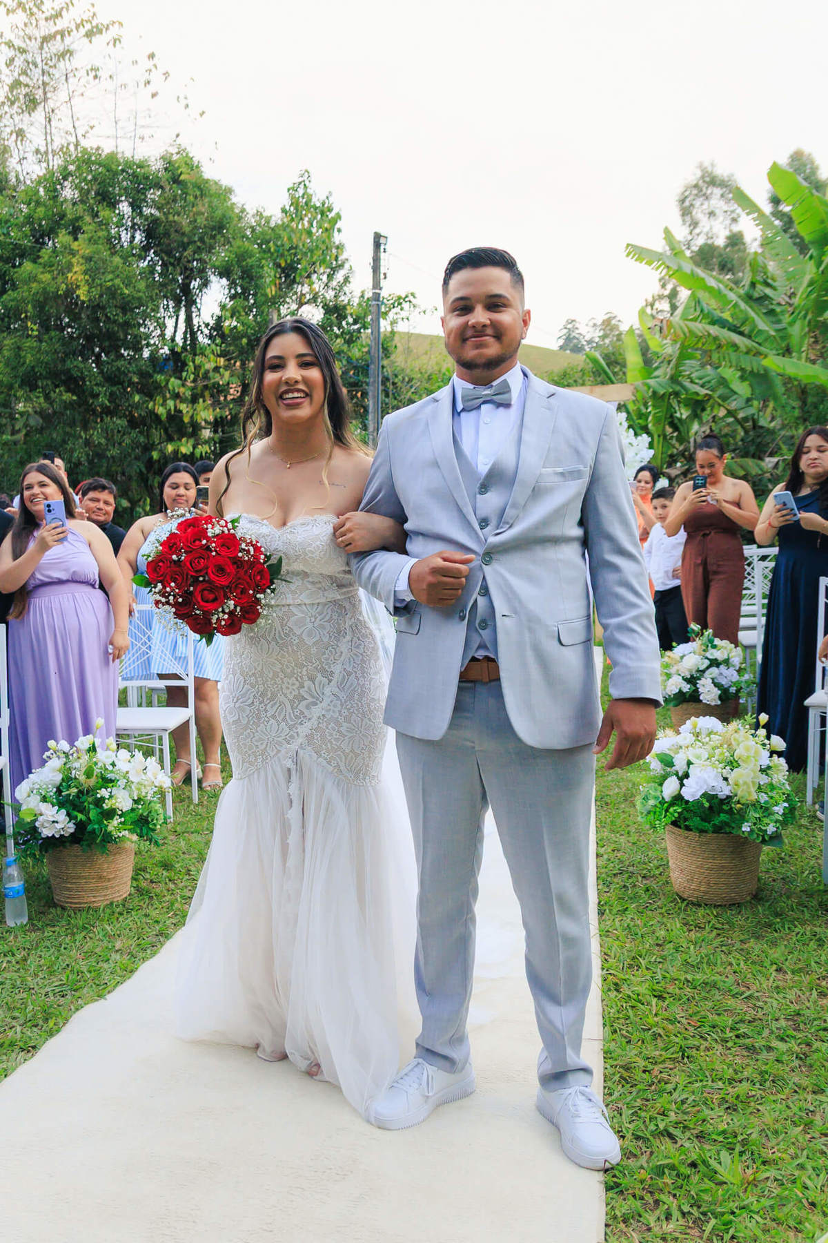 Harluine e Ozeias entrando juntos na cerimônia de casamento ao ar livre.