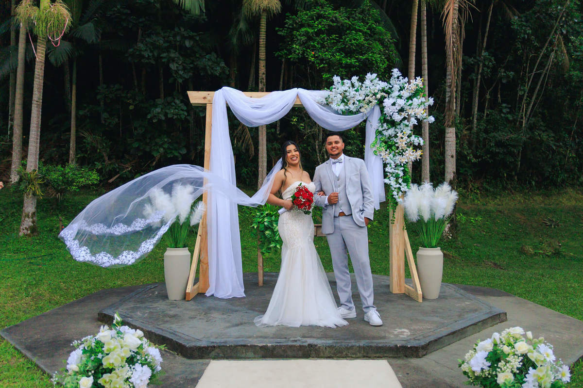 Decoração de casamento ao ar livre com altar branco em meio à natureza.