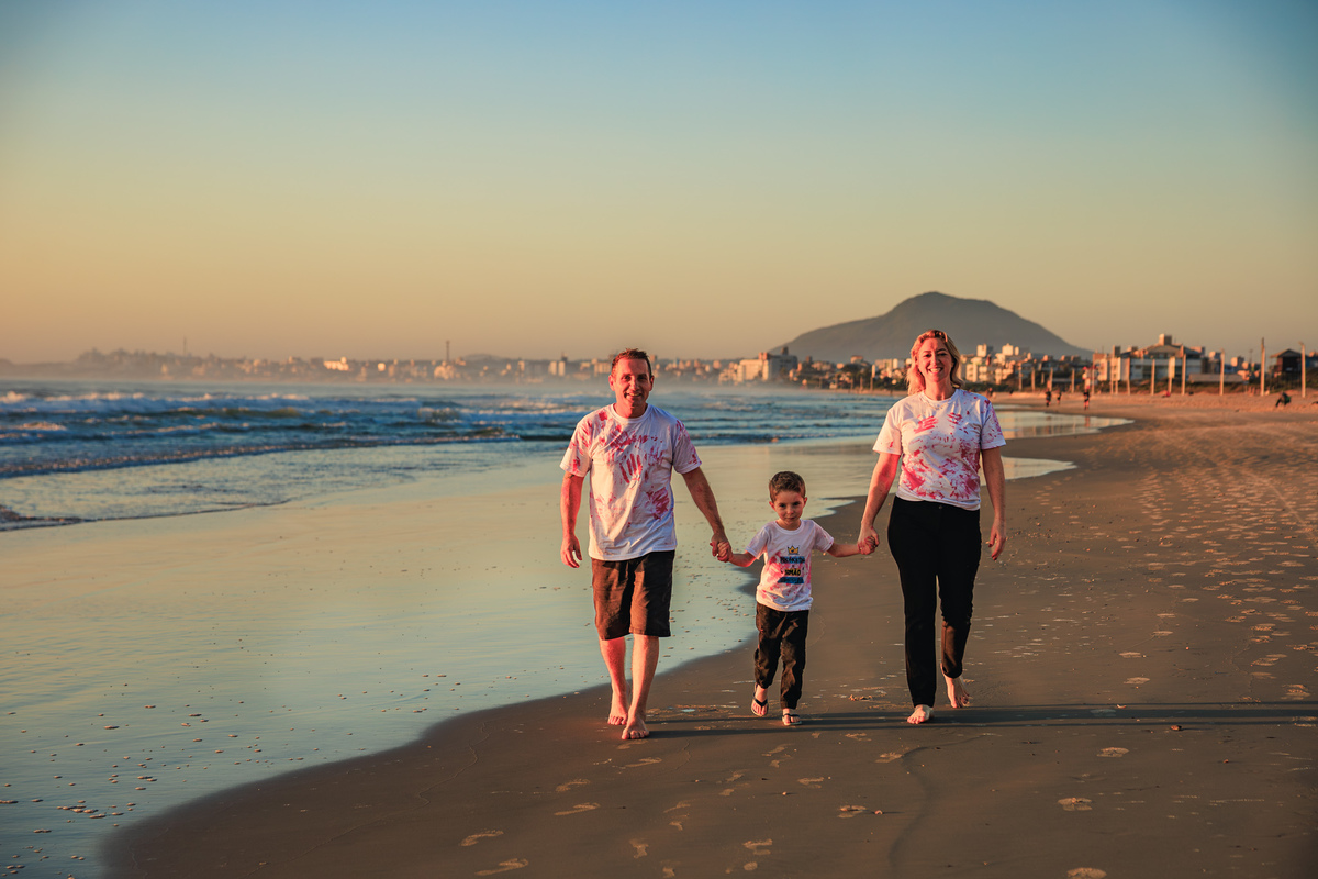 Família caminhando de mãos dadas pela Praia dos Ingleses.