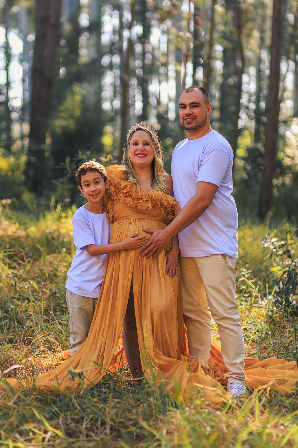 Família posa unida durante ensaio de gestante com vestido dourado em
Florianópolis.