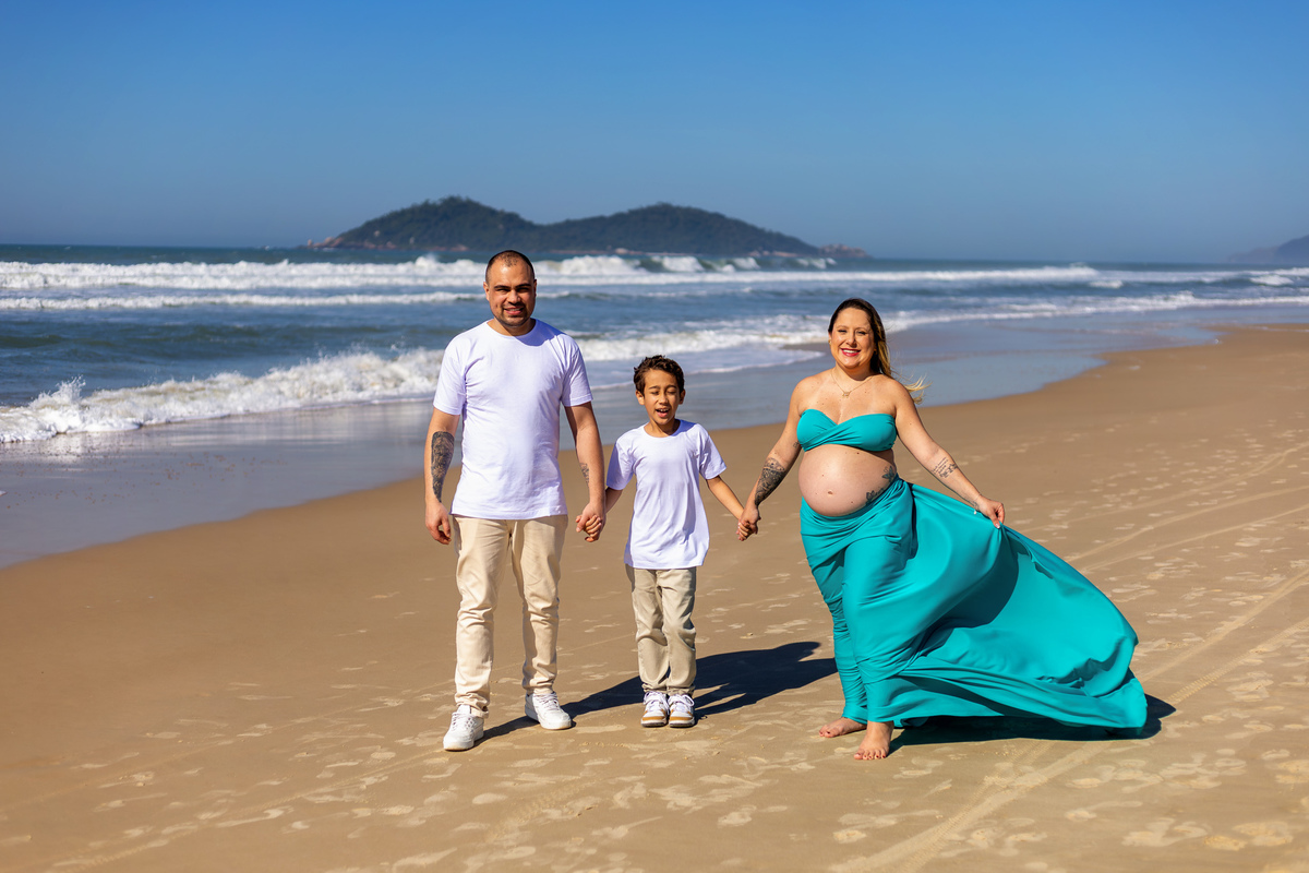 Família caminha de mãos dadas durante ensaio de gestante na praia no
Sul da Ilha.