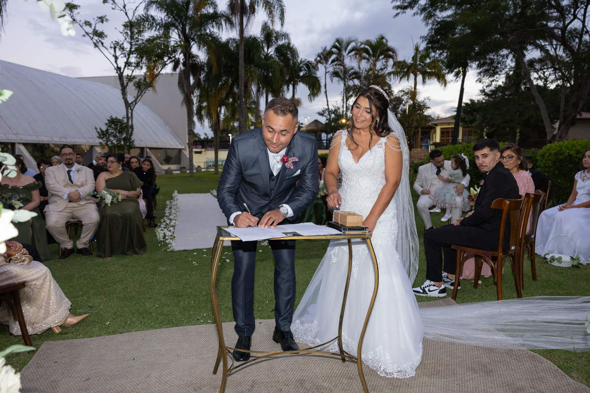 Casal assina o registro da cerimônia no jardim do Sesc Cacupé.