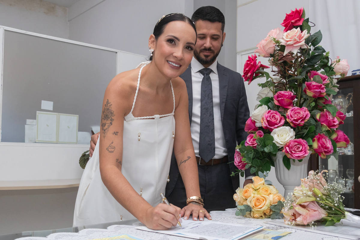 Noiva assina o registro do casamento durante a celebração conjunta.