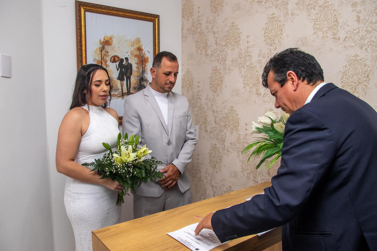 Taise Silva e seu esposo acompanham a
condução da cerimônia no cartório.
