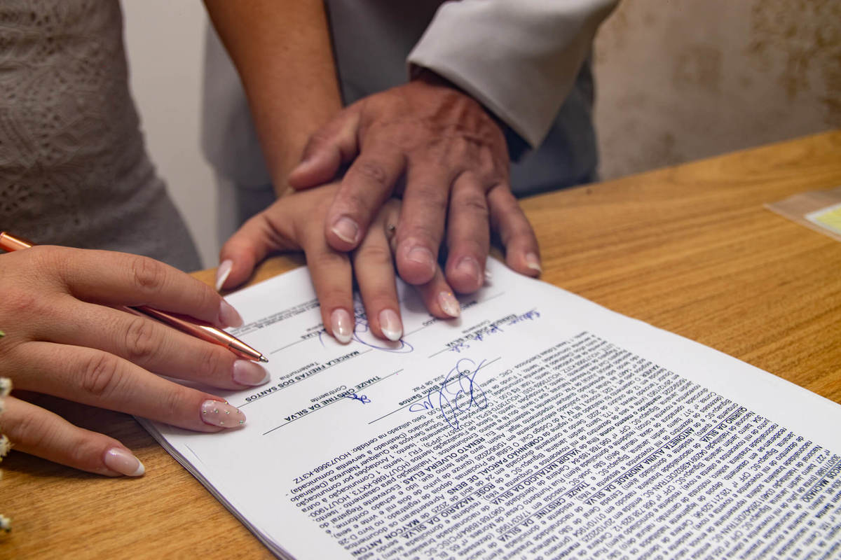 Detalhe das mãos do casal sobre o
documento do casamento