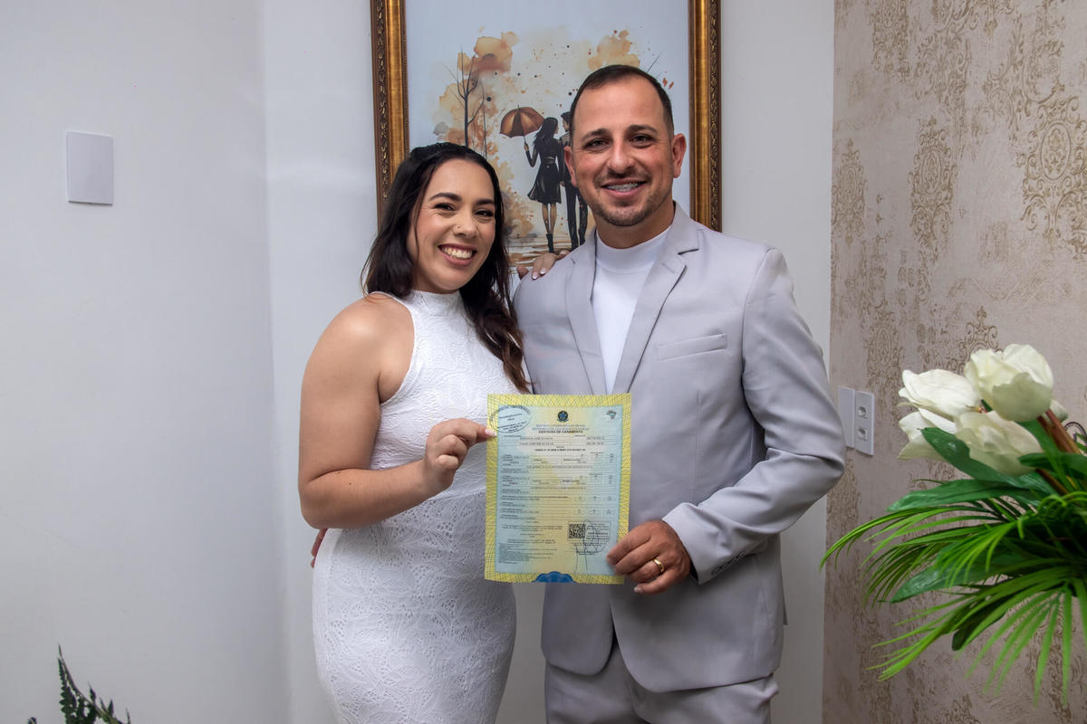 Taise Silva e seu esposo exibem a certidão
após oficializarem a união