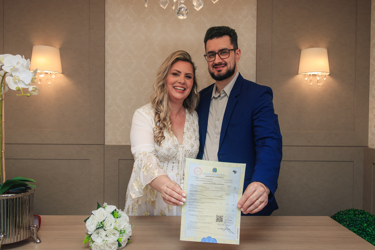 Casal sorrindo e mostrando a certidão de casamento após a cerimônia no cartório.