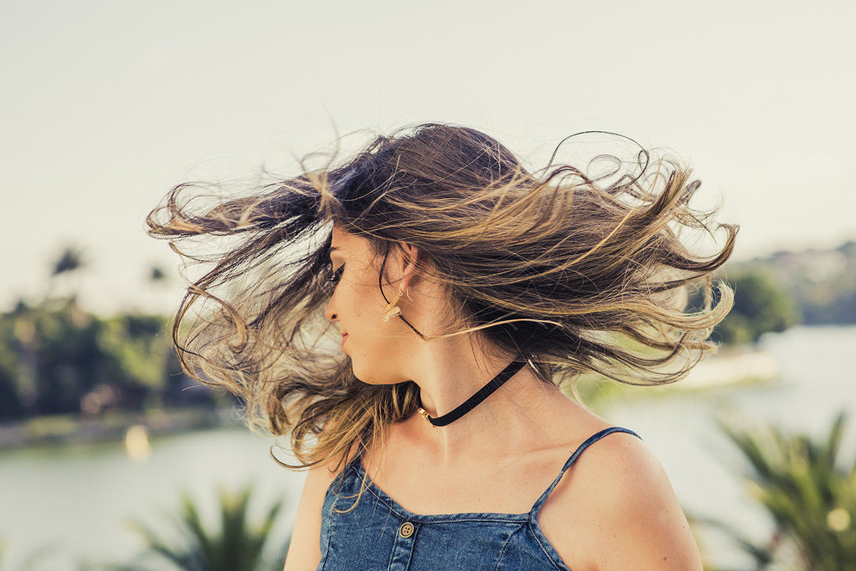 Modelo balançando os cabelos no ensaio externo de debutante com uma bela vista de fundo da lagoa da Pampulha no click do fotógrafo de casamentos em Belo Horizonte BH MG