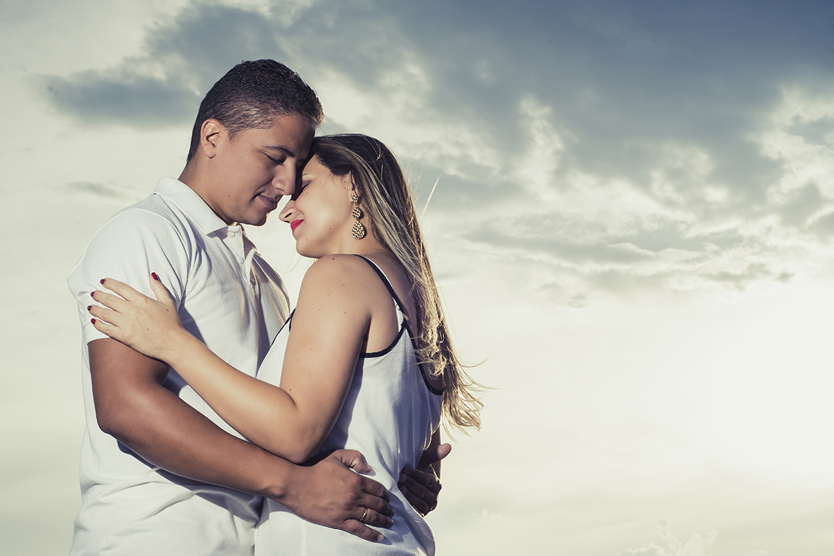 Noivos se abraçando com olhos fechados no click do fotografo de casamentos em Belo Horizonte BH MG com um belíssimo pôr do sol de fundo