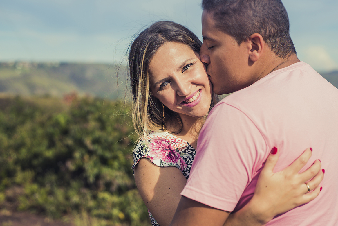 Noivos beijando a noiva sorrindo feliz no click do fotografo de casamentos Belo Horizonte BH MG em um dia ensolarado