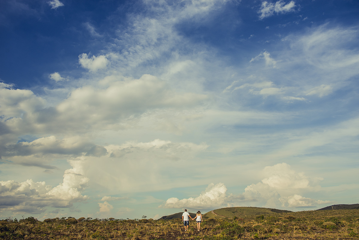Casais caminhando de mãos dadas ruma as montanhas da serra do rola moça e um imenso céu azul no ensaio pre wedding