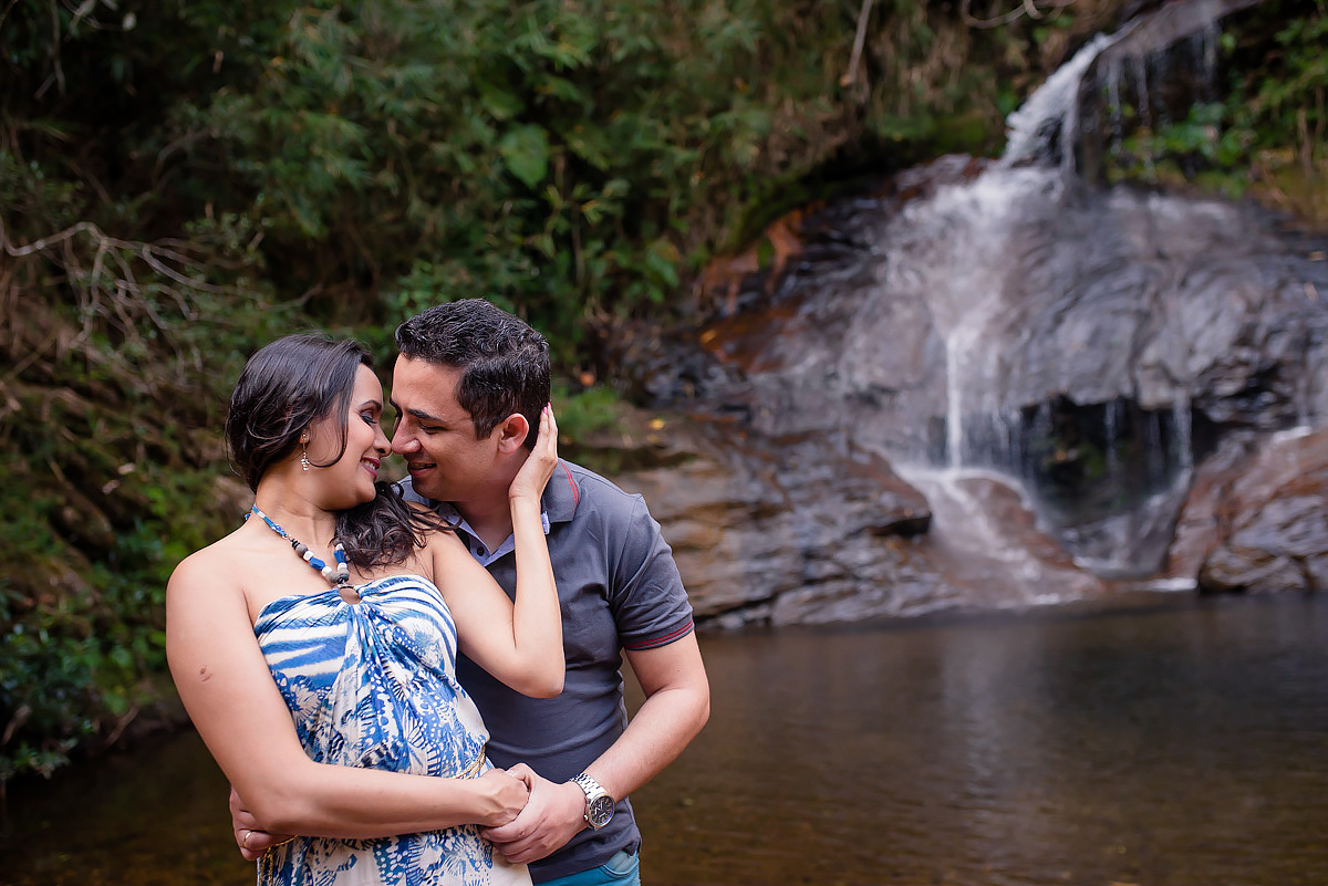 casal de noiva s se abraçando em frente a cachoeira