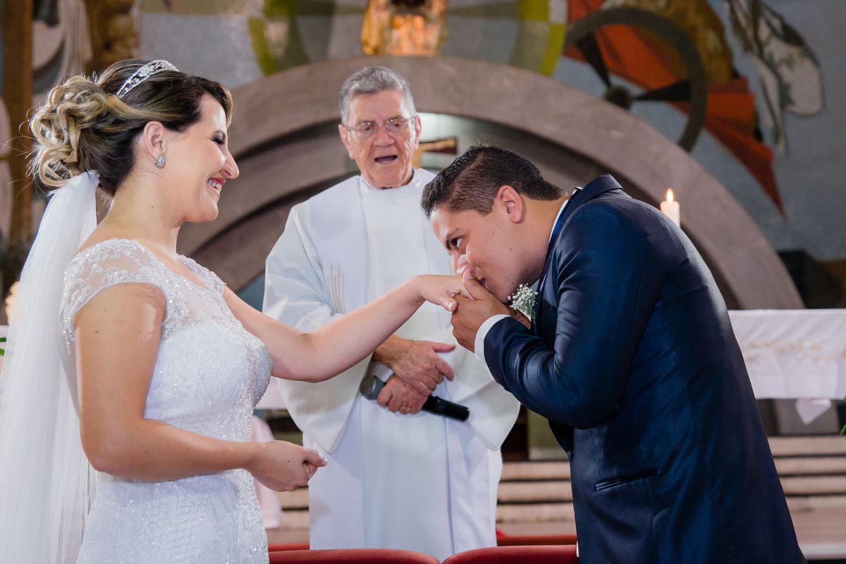 noivo beijando a aliança da noiva no altar da igreja nossa senhora do Carmo em belo horizonte