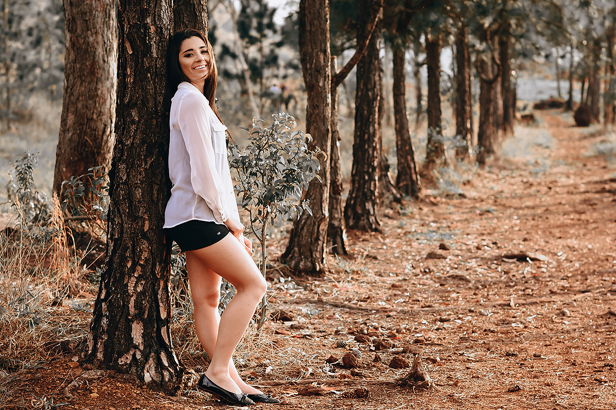 modelo apoiada na arvore e sorrindo no ensaio externo feminino feito em belo horizonte