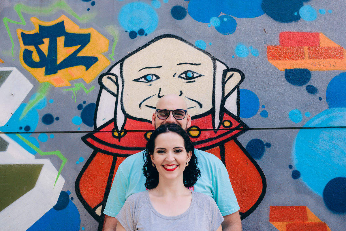 casal posando para o ensaio pre wedding em frente a uma parede com grafite 