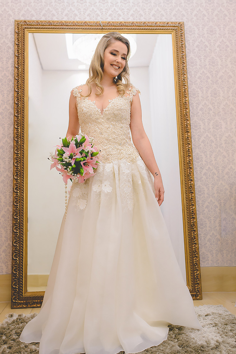 noiva com cuque de rosas na mão com vestido de noiva off white