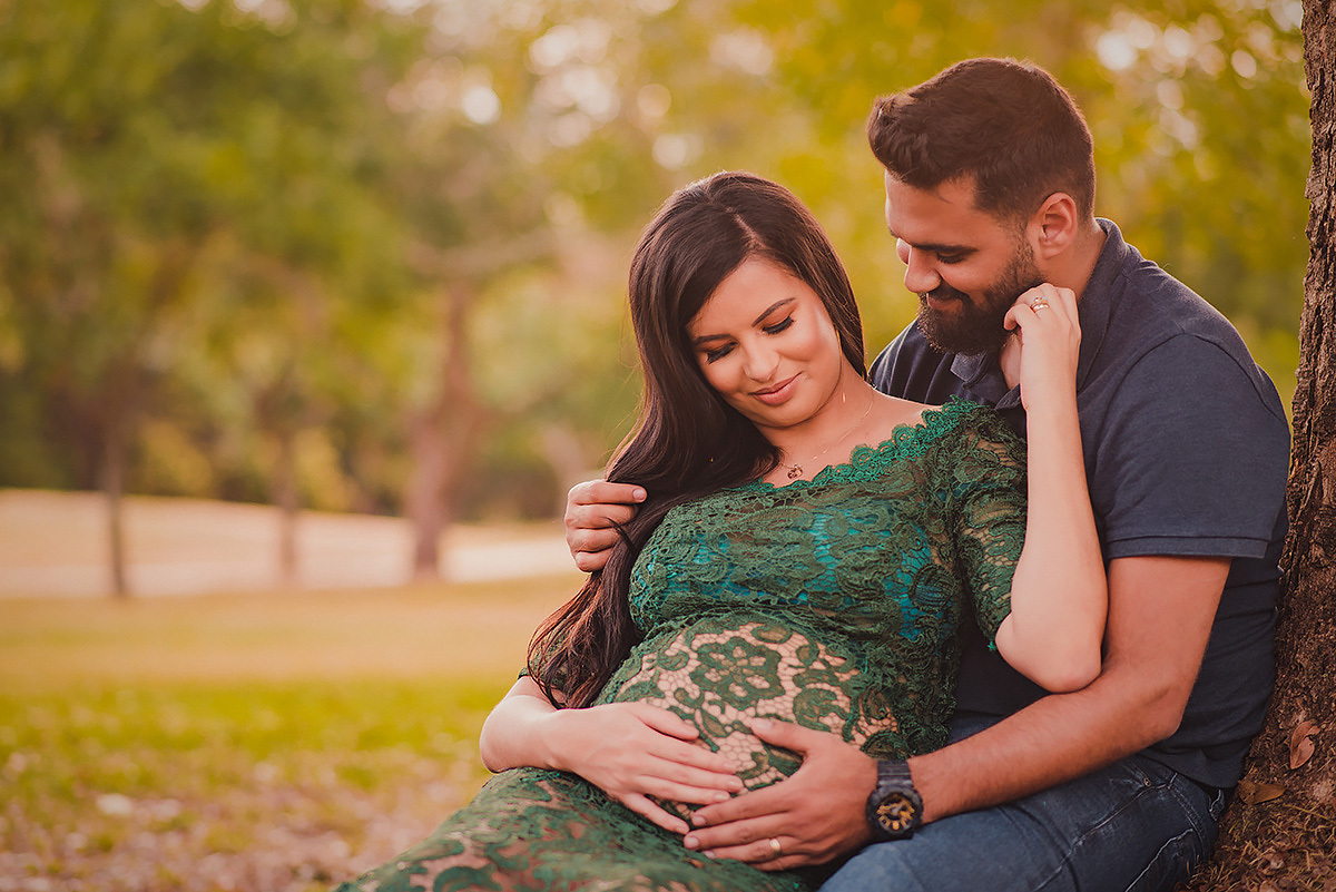 Ensaio de Gestante em BH Belo horizonte parque ecológico da Pampulha - casal sentado no gramado acariciando a barriga da gestante
