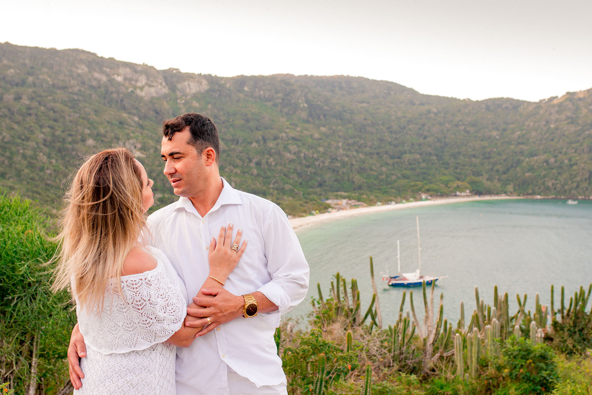 casal abraçado com a vista da praia do forno ao fundo no pre wedding na praia em cabo frio