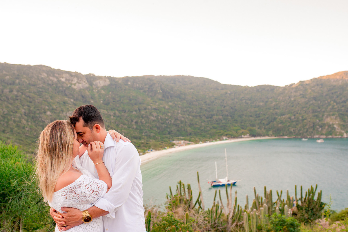 noivo abraçando a noiva com a vista da praia do forno ao fundo no pre wedding na praia em cabo frio RJ