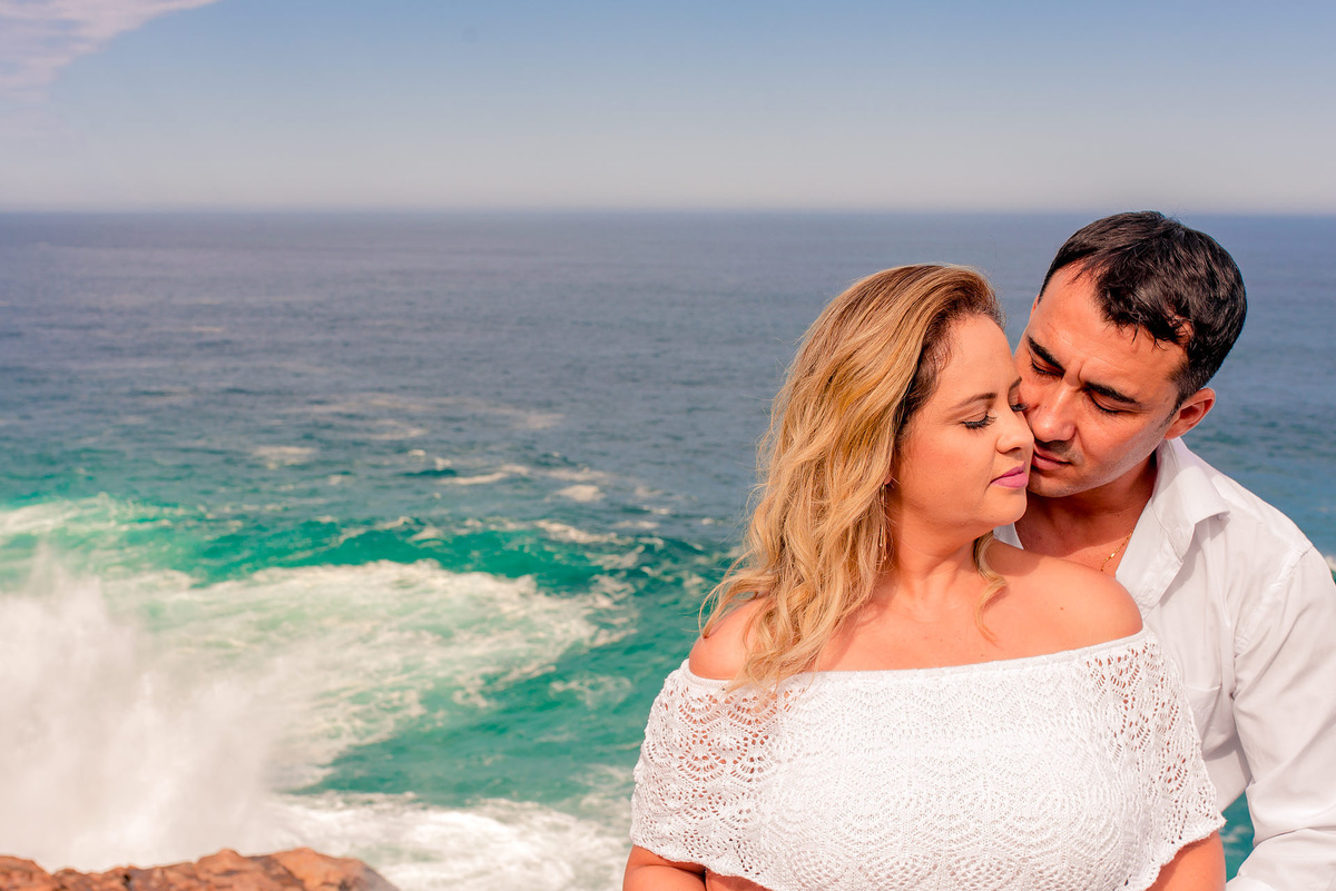 noivos abraçados com o mar ao fundo no ensaio pre wedding feito em arraial do cabo