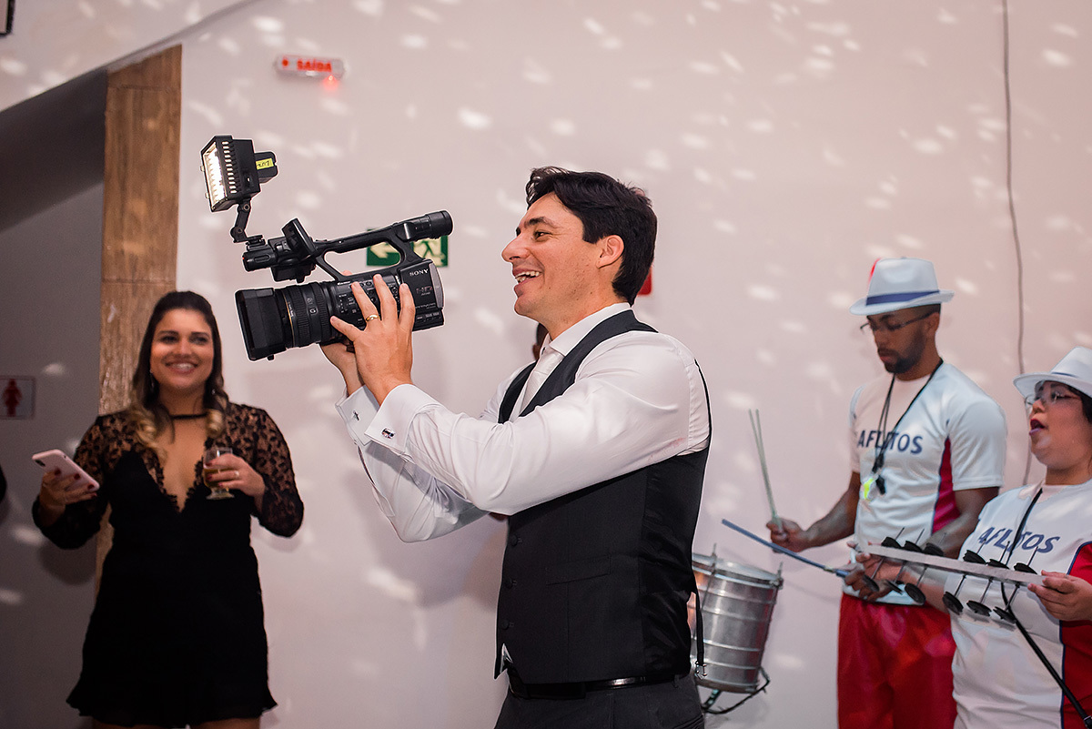 noivo feliz na festa com câmera na mão no casamento em bh