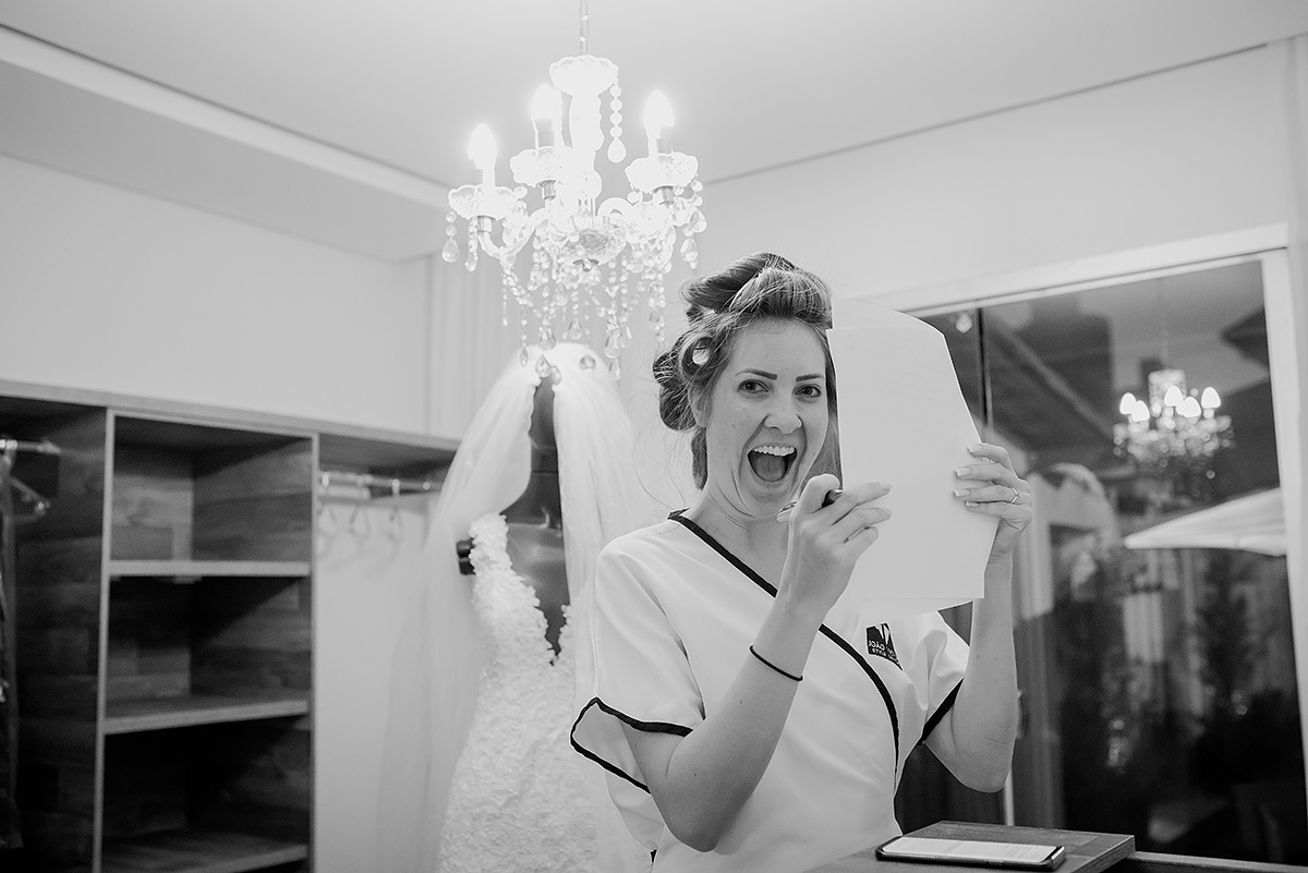 noiva feliz no dia da noiva em bh com o vestido de noiva ao fundo