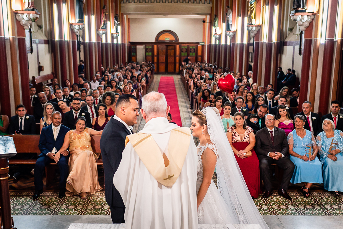 padre abençoando as alianças no casamento realizado na capela do colégio arnaldo em bh