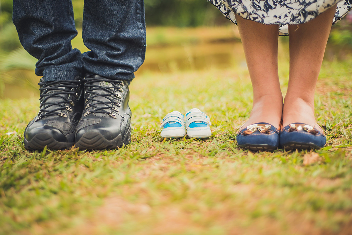 Sapatinho de bebê junto com os pés dos pais fotografados pelo fotógrafo João Paulo no parque das águas em belo horizonte BH MG