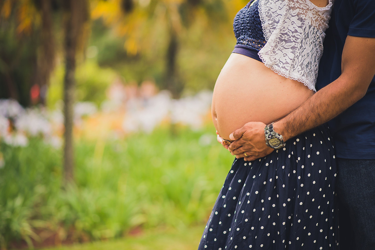 Pai segurando a barriga da gestante no ensaio de gestante no parque das águas em belo horizonte BH MG