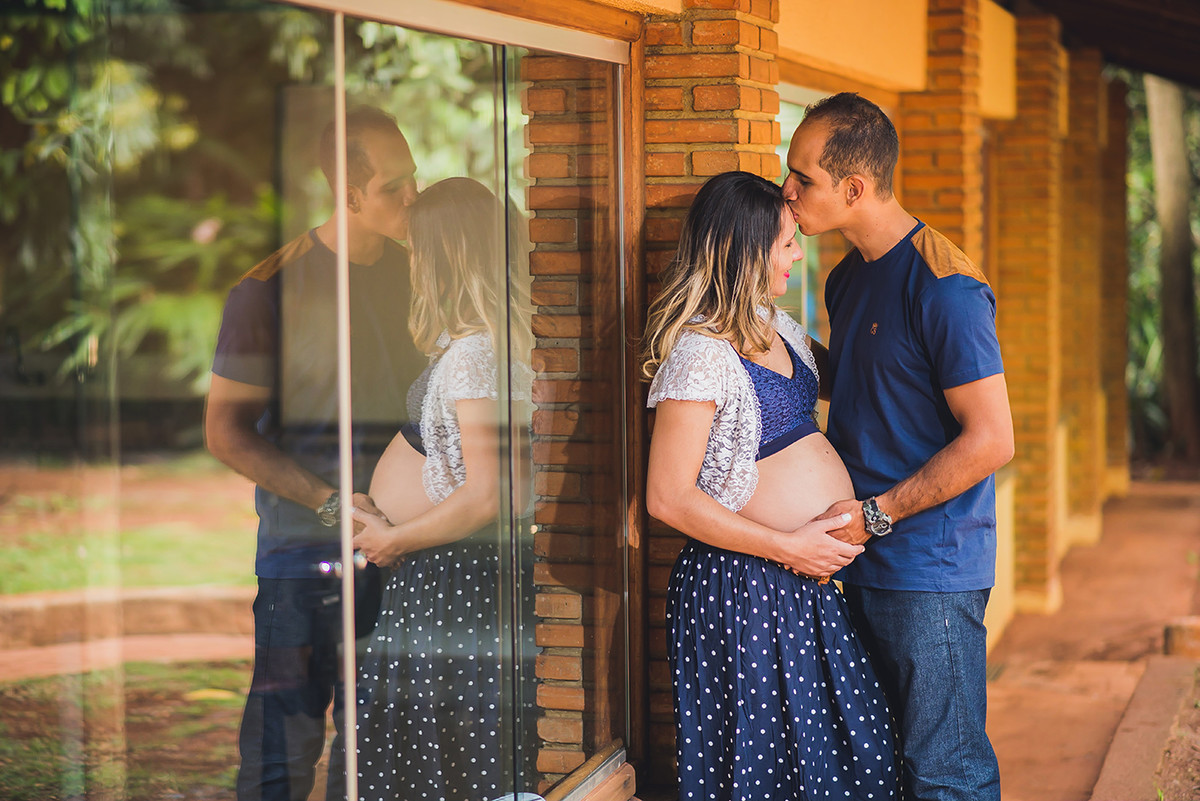 Pai beijando a testa da gestante com reflexo no vidro fotografado pelo fotografo de gestante João Paulo em BH