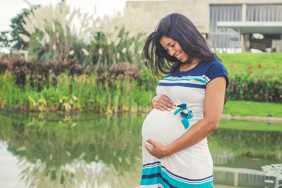 Gestante no museu de arte na Pampulha acariciando a barriga e sorrindo no do fotógrafo de gestantes em Belo Horizonte BH MG